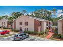 Exterior view of an apartment with red brick accents, well-maintained landscaping, and parking area at 21032 Voyager Blvd # 8, Land O Lakes, FL 34638
