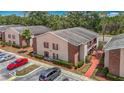 Exterior view of an apartment with red brick accents, well-maintained landscaping, and parking area at 21032 Voyager Blvd # 8, Land O Lakes, FL 34638