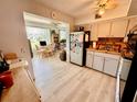 Kitchen flowing to a dining room with light wood flooring and featuring white appliances and wooden table at 2434 Australia E Way # 38, Clearwater, FL 33763