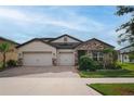 Attractive single Gathering home featuring a well-manicured lawn, stone accents, and a spacious three-car garage at 3091 King Fern Dr, Wimauma, FL 33598