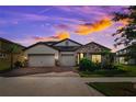 Beautiful home showcasing a three car garage, brick driveway and stone facade, perfect for curb appeal at 3091 King Fern Dr, Wimauma, FL 33598