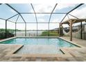 Inviting screened-in pool area with a hammock, brick pool deck, and lake view, creating a relaxing outdoor oasis at 3091 King Fern Dr, Wimauma, FL 33598