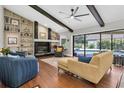 Bright living room features a stone fireplace, wood floors, built in shelves and opens to a pool at 4049 Wellington Pkwy, Palm Harbor, FL 34685