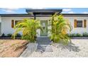 The front entrance shows a black trimmed awning, decorative shutters, and is framed by lovely palm trees at 4684 72 N Ave, Pinellas Park, FL 33781