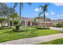 Charming single-story home featuring manicured landscaping, mature trees, and a driveway on a sunny day at 9348 Deer Creek Dr, Tampa, FL 33647