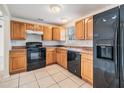 Well-lit kitchen featuring wood cabinets, a black oven range, and a black refrigerator at 10110 Pepperidge Ct, Tampa, FL 33615