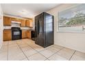 Bright kitchen featuring tile floors, wood cabinets, and modern black appliances at 10110 Pepperidge Ct, Tampa, FL 33615