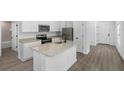 Modern kitchen features white cabinets, stainless steel appliances, a spacious island, and wood flooring at 11192 Humber Rd, Weeki Wachee, FL 34614