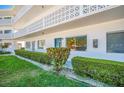 Exterior view of a condo building with a blue door, decorative white lattice balcony and manicured landscaping at 11224 82Nd Ave # 104, Seminole, FL 33772