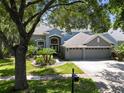 Charming two-story home featuring a three-car garage, mature trees, and a lush green lawn at 11723 Gothic Ln, Tampa, FL 33626