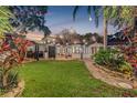 Expansive backyard with lush lawn, ambient string lights, and vibrant tropical landscaping at 122 Miramar Ne Blvd, St Petersburg, FL 33704