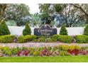 The Carrollwood Village entrance sign is surrounded by lush landscaping and colorful flower beds at 14116 Trouville Dr, Tampa, FL 33624