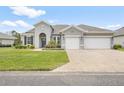 Inviting single-story home featuring a symmetrical facade, lush lawn, and a brick driveway at 19819 Tattnall Way, Brooksville, FL 34601