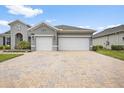 A home showcasing a spacious two-car garage and brick driveway, enhanced by landscaping and neutral color palette at 19819 Tattnall Way, Brooksville, FL 34601