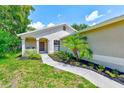 Inviting home entrance with a beautifully landscaped yard and concrete walkway to the front door at 22943 Sills Loop, Land O Lakes, FL 34639