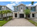 Charming two-story townhome featuring a paver driveway, attached garage, and beautiful landscaping at 2816 Grand Kemerton Pl, Tampa, FL 33618