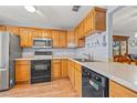 Efficient kitchen with wood cabinets, black appliances, and a view into the dining area at 2919 Fig Ct, Palm Harbor, FL 34684