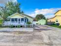 Charming yellow home with a picket fence, covered porch, and a matching storage shed, set against a bright blue sky at 2928 W Arch St, Tampa, FL 33607