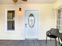 Inviting front porch with neutral paint, tiled floor, ceiling fan, front door with decorative glass, and outdoor furniture at 2928 W Arch St, Tampa, FL 33607