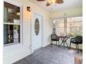 Inviting front porch with neutral paint, tiled floor, ceiling fan, front door with decorative glass, and outdoor furniture at 2928 W Arch St, Tampa, FL 33607