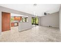 Open-concept living room with tile floors, ceiling fan, and sliding door to screened patio at 2986 Cypress Green Dr, Palm Harbor, FL 34684