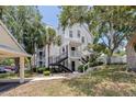Exterior view of the two-story condo building with inviting stairs, landscaping, and covered parking at 3301 Haviland Ct # 203, Palm Harbor, FL 34684