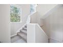 Bright staircase with carpeted steps, white railings, and natural light from nearby windows at 3301 Haviland Ct # 203, Palm Harbor, FL 34684