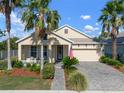 Inviting one-story home with an attached garage, landscaped garden, and charming front porch area at 5102 Coastal Scene Dr, Apollo Beach, FL 33572