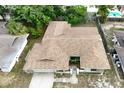 Aerial view of single-story home showcasing the roof, landscaping, driveway, and proximity to neighboring houses at 613 Sandy Hollow Rd, Tarpon Springs, FL 34689