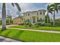 Two-story home showcasing lush landscaping, a paver driveway, a three-car garage, and a second-story balcony at 6468 Rubia Cir, Apollo Beach, FL 33572