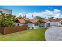 Exterior of a well-maintained home with a tile roof, a fenced yard, and tropical landscaping at 7125 S Shore S Dr, St Petersburg, FL 33707