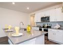 Modern kitchen boasts white cabinets, stainless steel appliances, gray countertops, and stylish backsplash at 9795 Crescent Ray Dr, Wesley Chapel, FL 33545