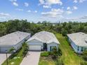 Aerial view of a new home featuring a meticulously landscaped yard in a quiet, wooded neighborhood at 10036 Beachwalk Dr, Englewood, FL 34223