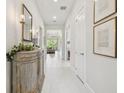 Bright hallway with white tile floors leading to the living area, with elegant decorations and art at 10036 Beachwalk Dr, Englewood, FL 34223