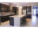 Modern kitchen featuring dark cabinets, granite countertops, and stainless steel appliances at 10431 Alcon Blue Dr, Riverview, FL 33578