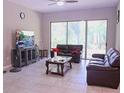 Comfortable living room features a ceiling fan, tiled floors, and a sliding glass door to the outside at 10431 Alcon Blue Dr, Riverview, FL 33578