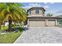 Well-maintained home featuring a paver driveway, three-car garage, and meticulously landscaped front yard at 11602 Sunburst Marble Rd, Riverview, FL 33579