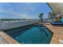 A sparkling pool surrounded by travertine tile and white fencing, overlooking a sandy beach at 13303 Gulf Ln, Madeira Beach, FL 33708