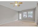 Neutral living room featuring carpeted floor, ceiling fan, and natural light from the front door and two windows at 16137 Churchview Dr, Lithia, FL 33547