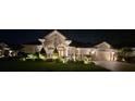 Nighttime view of a home, showcasing illuminated landscaping and a tile roof at 17923 Arbor Haven Dr, Tampa, FL 33647