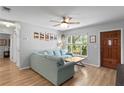 Bright living room features a large window overlooking the yard, a blue sectional couch, and hardwood floors at 2136 Cunningham Dr, Clearwater, FL 33763