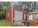 Spacious red steel garage with a roll-up door, a side entrance, and a window at 3424 16Th E St, Bradenton, FL 34208