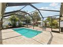 Screened-in pool area showcasing a pool, beautiful stone patio, lush tropical plants, and an outdoor seating area at 3966 High Bluff Dr, Largo, FL 33770