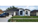 Charming single-story home with an attached garage, arched windows, and a manicured lawn and black car at 6213 Ashfield Pl, Wesley Chapel, FL 33545