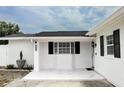 Inviting front porch with a tile floor, white brick walls, and black shutters at 6508 Lenore Dr, Tampa, FL 33634