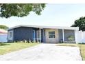Charming single-story home featuring a textured exterior, landscaped yard, and a bright blue front door at 6527 S West Shore Cir, Tampa, FL 33616