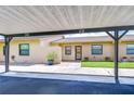Exterior view under carport showing the unit's entrance, landscaping, and well-kept facade at 6550 Teak Ct, Zephyrhills, FL 33542