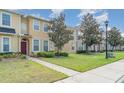 Inviting curb appeal with landscaped lawn and a townhome featuring a red front door at 6920 Towering Spruce Dr, Riverview, FL 33578