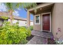 Inviting home entrance with brick walkway, colorful plants, and a striking red front door at 8719 Winning Fields Rd, New Port Richey, FL 34655