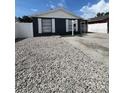 View of single-story home with dark siding, white trim, stone ground cover, and 'For Sale' sign at 9106 Telford Ct, Tampa, FL 33615